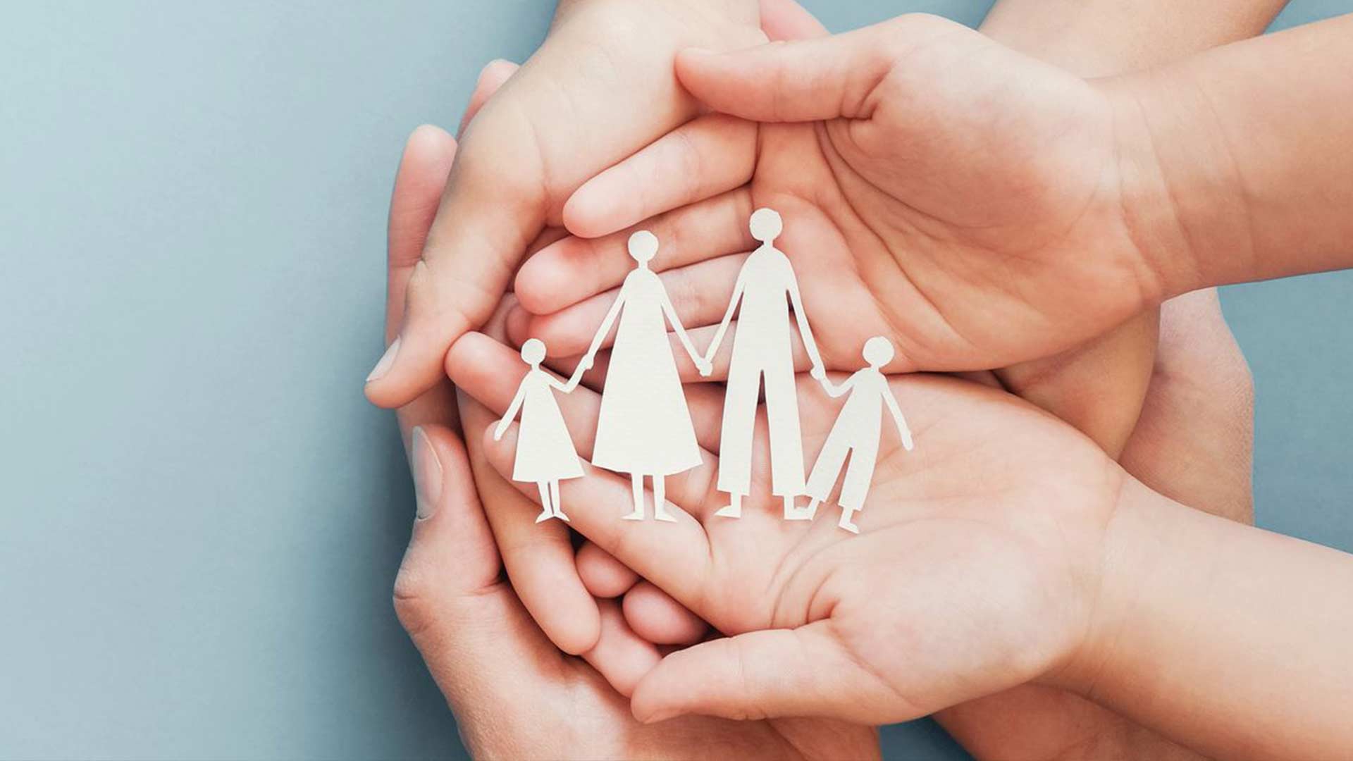 Paper Cutouts of a family hand in hand sitting within cupped hands